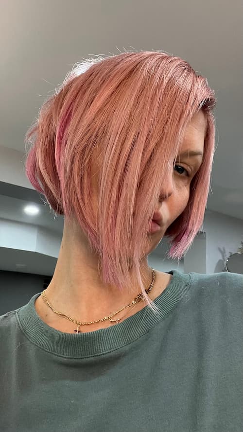 Marlena Hair showcasing a vibrant pink hair color with an edgy bob haircut, representing bold and modern hair artistry